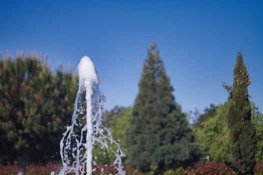 Fountain water splashes under a clear blue sky in a beautiful park during a sunny day photo