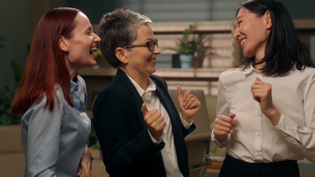 Happy multicultural women celebrate victory winning females dance colleagues coworkers successful group diverse business people office team businesswomen good news offer deal achieve excited together photo