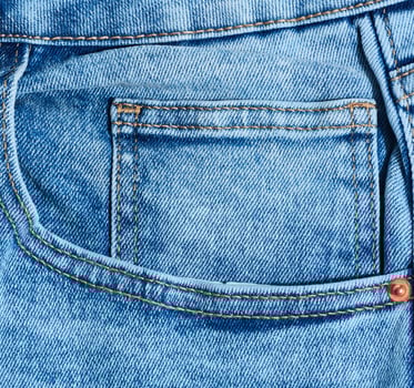Close up of blue denim jeans showing a front pocket corner with distinct orange stitching detail photo