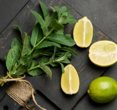 Bunch of fresh green mint on wooden board and lime wedges, top view. Cocktail ingredient photo