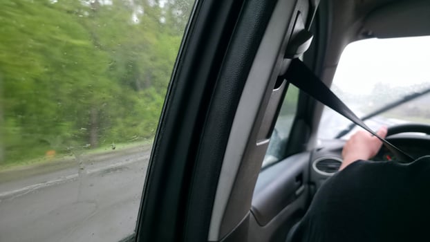 Driving in the rain. Interior view from the passenger seat. Wet window, blurred scenery. Focus on safety belt. Travel, transportation concept. photo