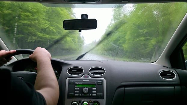 Driving in heavy rain. Interior view from the driver's seat. Wet windshield, blurred road and trees. Focus on the journey. Travel, transportation concept. photo