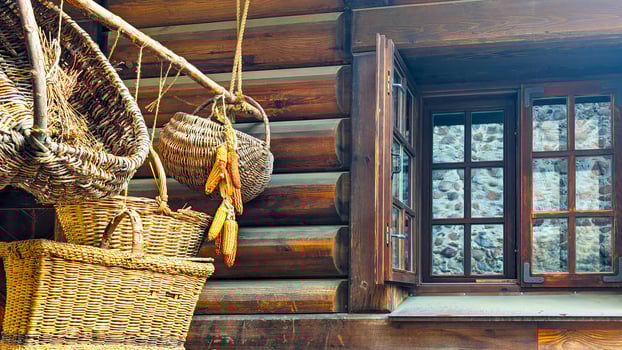 Wicker baskets and dried corn hanging by a rustic wooden house window, traditional countryside decor photo