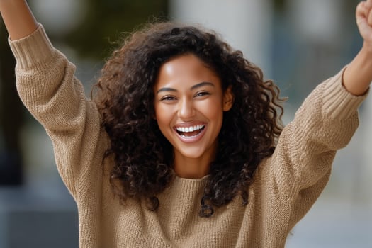 A woman with curly hair is smiling and raising her arms photo