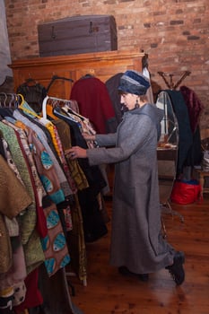 beautiful woman wearing a warm coat and an original wool hat viewing clothes in a fashion laboratory photo