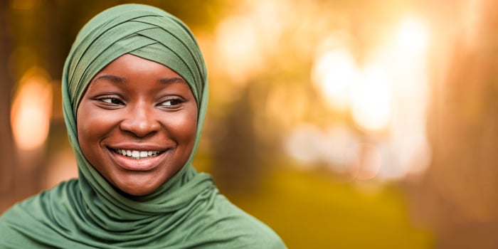 Closeup Shot Of Beautiful Black Islamic Lady In Hijab Standing Outdoors And Looking Aside. Portrait Of Smiling African Muslim Woman In Green Headscarf Standing Outside, Selective Focus, Copy Space photo