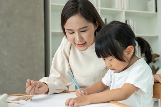 Happy Asian mother playing learning paint for little girl. Funny family is happy and excited in the house. Mother and daughter having fun spending time together. Holiday, Activity photo