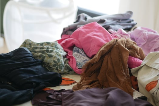 Clothes piled on a table in a bright room during the day photo