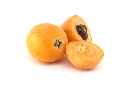 A collection of ripe loquats, with one cut to reveal the seeds, set on a bright white backdrop. photo