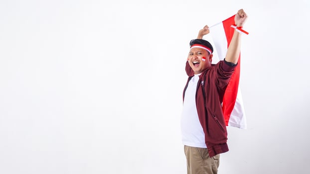 Excited Asian man holding Indonesia flag as concept of independence day isolated on white background photo