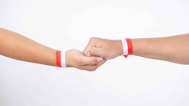 Two men hands with red and white wristband gripping each in firm handshake other isolated on white background photo