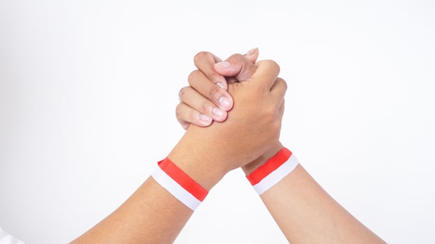 Close up of two men hands with red and white wristband doing unity handshake or clasping isolated on white background photo