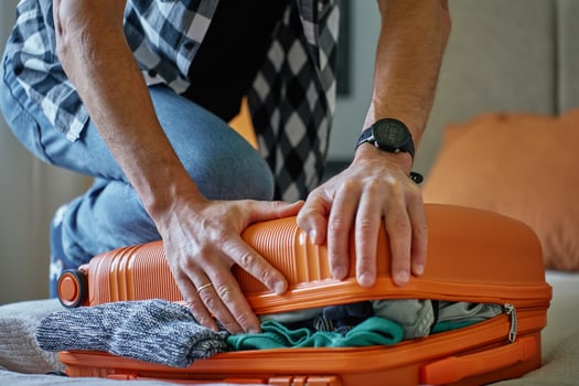 Man trying to close over packed suitcase before trip photo