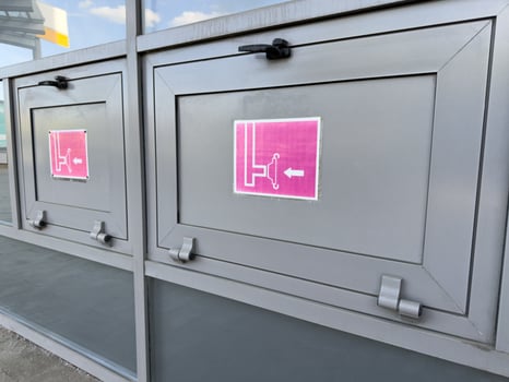 Metal fire hose cabinets with emergency signs and pictograms indicating hose reel direction, installed on building exterior as part of public fire safety system and modern infrastructure photo