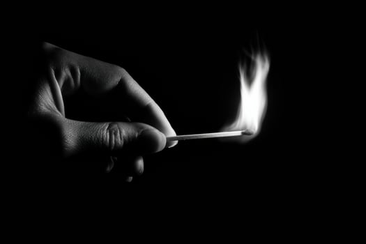 A person holding a matchstick in the dark photo