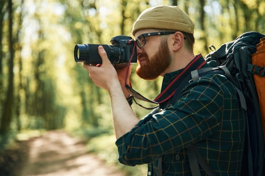Photographer, with camera. Bearded, man is in the forest at daytime photo