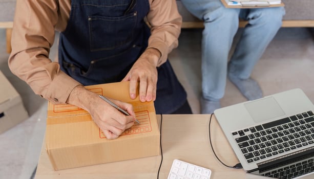 Creative social media marketer preparing product packages during a live stream in their home office photo