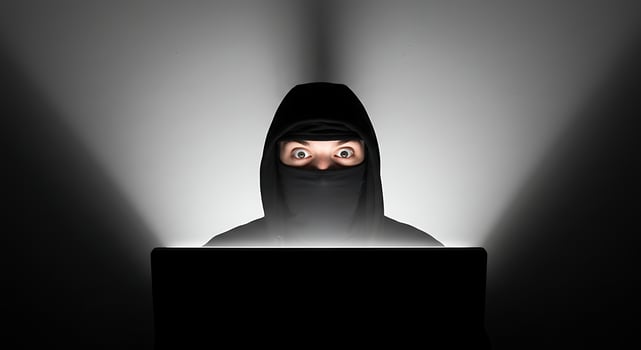 Person in Hood Using Computer at Night with Focused Expression photo
