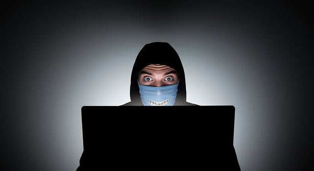 Person in Mask Using Laptop at Night with Intense Gaze photo