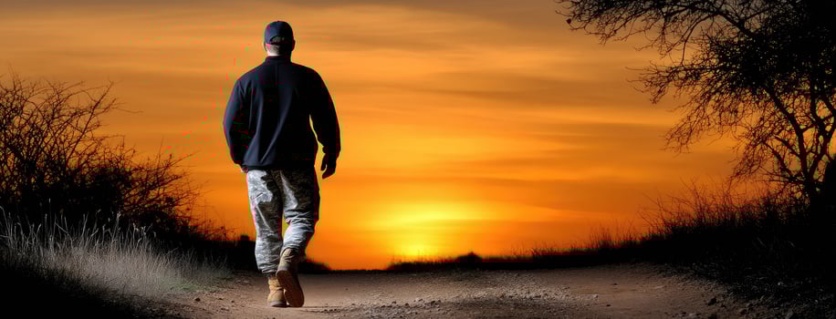A man walking on a dirt road at sunset photo
