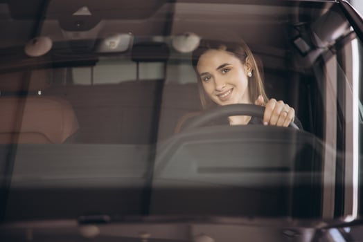 Businesswoman smiling while driving new car at dealership photo