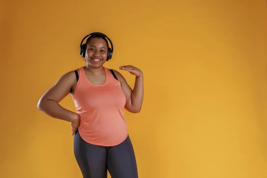 Enjoying ,music, in,, headphones. African American woman is in the studio against yellow background photo