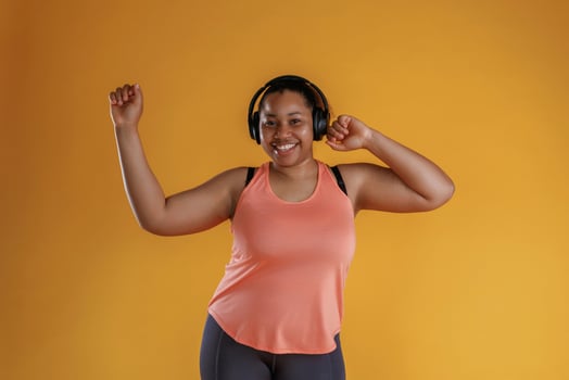 Enjoying music,, in headphones. African American woman is in the studio against yellow background photo