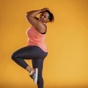 Side, view,, posing. In leggings. African American woman is in the studio against yellow background photo