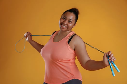 Jumping rope,, standing. African American woman is in the studio against yellow background photo