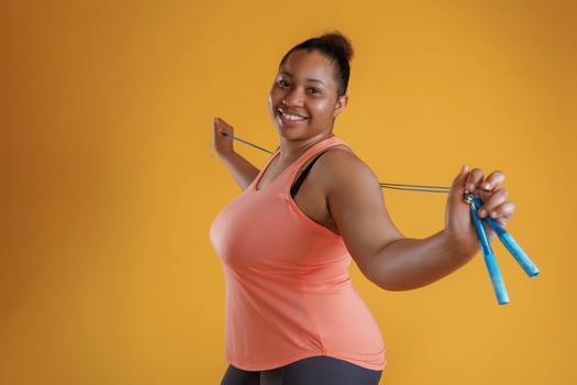 Jumping rope, standing.. African American woman is in the studio against yellow background photo