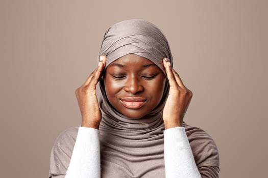 Headache Concept. Sad Black Muslim Lady In Hijab Suffering From Migraine Pain, Touching Her Temples, African Islamic Woman Feeling Unwell While Posing Over Light Background In Studio, Copy Space photo