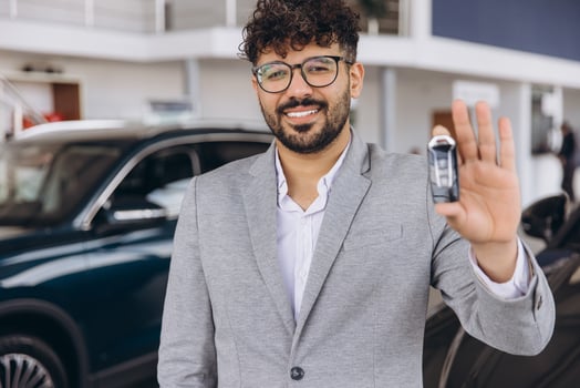 Smiling Car Salesman Showing New Car Key in Dealership photo