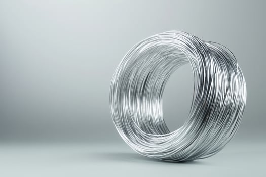Metallic wire coil displayed on a smooth grey background highlighting its shiny surface and intricate arrangement photo