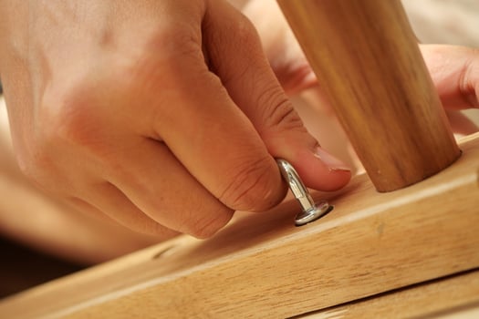 Hand securing metal latch on wooden furniture under bright sunlight photo