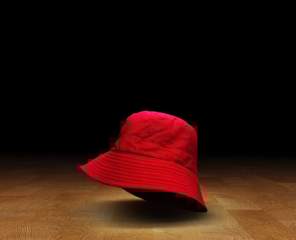 Red bucket hat on gym wooden floor, black background photo