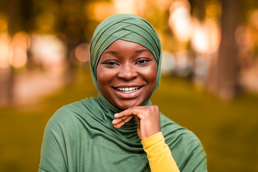 Cheerful Beautiful African Muslim Lady In Hijab Posing Outdoors, Smiling At Camera. Portrait Of Positive Black Islamic Woman In Headscarf Standing In Autumn City Park, Selective Focus, Free Space photo