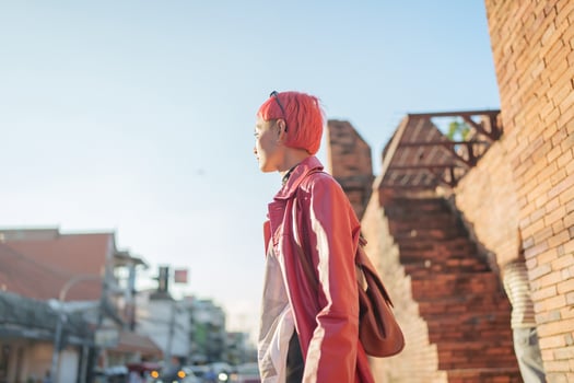Asian woman tourist of local city Southeast trendy pink hairstyle young female punk traveler walking around in town photo