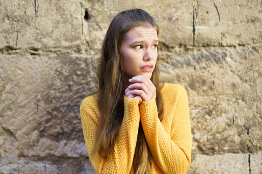 A young woman is expressing her deepseated feelings of anxiety against a rustic wall photo