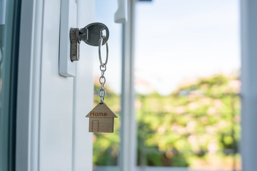 Landlord key for unlock house is plugged into the door. Second hand house for rent and sale. keychain is blowing in the wind. mortgage for new home, buy, sell, renovate, investment, owner, estate photo