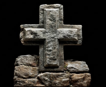 Medieval stone cross on rocky base in dark setting photo