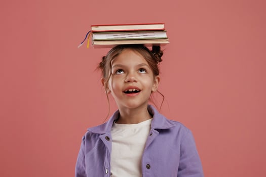 Notepads on the head. ..Cute, little girl is against pink background photo
