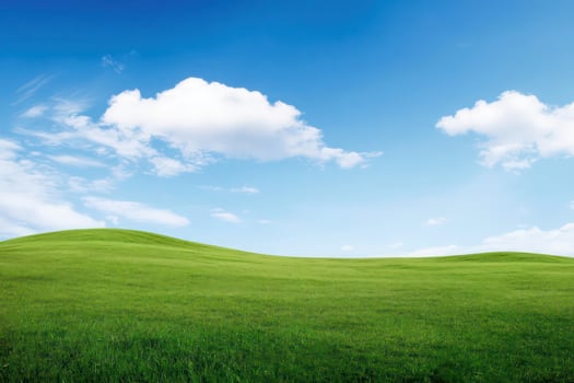 Serene Green Rolling Hills Landscape Under a Blue Sky with Fluffy Clouds photo