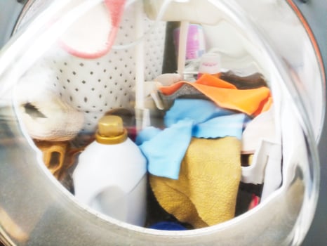 Laundry machine with clothes and cleaning product. Represents chores, routine, domesticity, and cleanliness. Use for articles on home life, cleaning, and lifestyle topics. photo