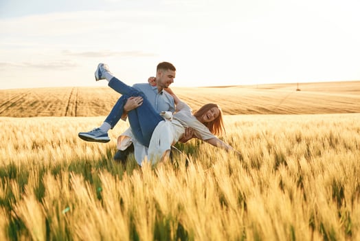 Having fun,, man is holding woman. Lovely beautiful couple are together on the agricultural field photo