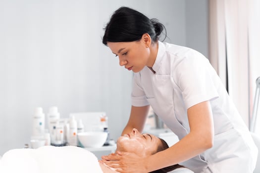 Masseuse providing facial massage to woman at cosmetology clinic photo