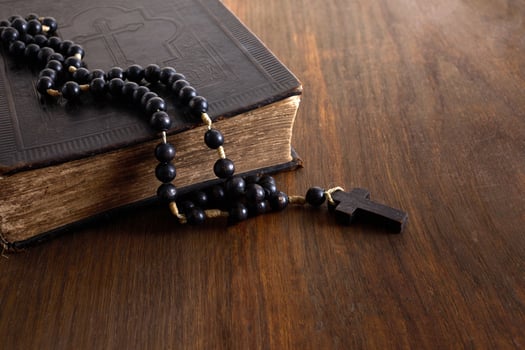 Vintage Holy Bible with lots of ornaments on the cover and old rosary on vintage wooden desk. Christianity concept photo