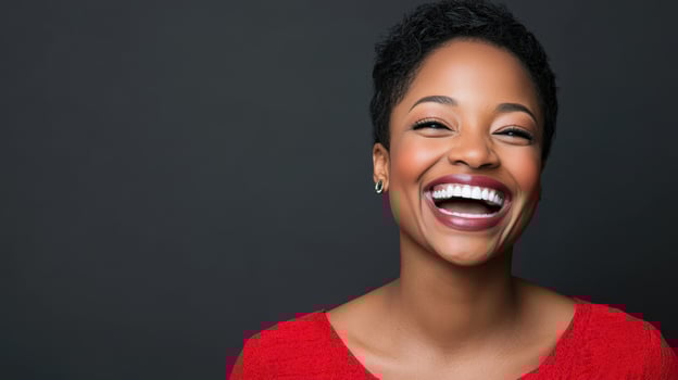 Joyful Laughing Woman Portrait Featuring Bright Smile and Red Top Against Solid Gray Backdrop photo