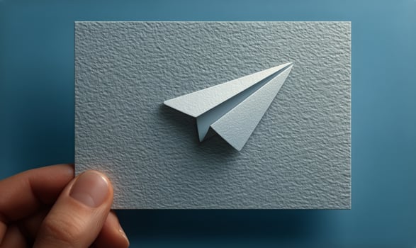 A person holding a paper airplane on a square card photo