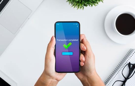 Fast Money Transfers. Woman Holding Smartphone With Transaction Completed Message On Screen, Sitting At Desk In Office, Top View photo