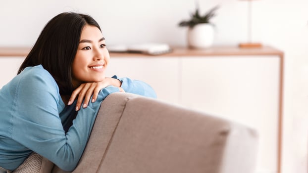 Weekend And Leisure Concept. Portrait of smiling asian woman having rest at home sitting on couch. Happy confident lady relaxing and leaning on sofa, enjoying free time and thinking about vacation photo